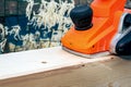 Background with an orange electric plane on the processed surface of a wooden beam Royalty Free Stock Photo