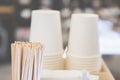 Background of paper cups and stirring sticks next to a coffee machine, cozy atmosphere of a coffee shop