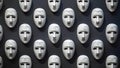The background is a pattern of various white masks expressing a certain emotion, symbolizing hypocrisy. Concept: contrast between