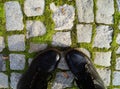 Black leather shoes on the background of paving blocks with moss-a walk in the city in the fall