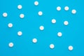 Background for pharmacy or medicine. White pills with medicine are on a blue uniform background, forming a polka dot pattern Royalty Free Stock Photo