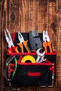 Background of professional electrician tools in the pockets of the loincloth on a wooden background Royalty Free Stock Photo