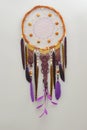 Background of purple dreamcatcher macrame feathers on gray wall