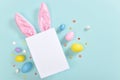 Background with rabbit ears and an empty piece of paper and Easter eggs. Royalty Free Stock Photo