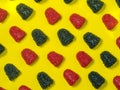 Background of red and black chewy candies in the form of berries on a yellow background. Sweets in the form of raspberries .