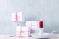 Background with red burning candle, wrapped boxes with presents against blue textured wall.