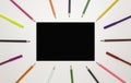 Background for school and student design. Colored pencils around a black rectangle. Free space for text. White background, top vie Royalty Free Stock Photo