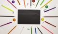 Background for school and student design. Colored pencils around a black rectangle. Free space for text. White background, top vie Royalty Free Stock Photo