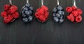 Background of six metal spoons with raspberries and blueberries on a black background Royalty Free Stock Photo