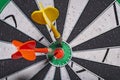 Background in soft focus with a darts board with a closeup of an arrow hitting the center and an opponent`s arrow stuck nearby