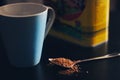 Spoon of cocoa powder and a blue cup. Royalty Free Stock Photo