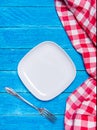 Background with squared empty white ceramic plate, antique silver cutlery on vintage weathered blue wooden boards and Royalty Free Stock Photo