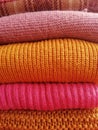 Background of a stack of knitted pink and orange sweaters