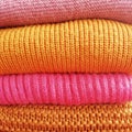 Background of a stack of knitted pink and orange sweaters