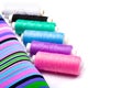 Background of striped fabric and spools of threads of different colors on a white background