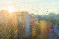 Background sunny window with shiny rain drops, view of the modern city.