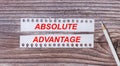 Background for text. White strips of paper with the text ABSOLUTE ADVANTAGE and a white pencil next to it on a wooden background Royalty Free Stock Photo