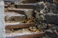 Background or texture of broken old, concrete steps on street with metal crossbars and fallen autumn, yellow leaves. Stone wall. Royalty Free Stock Photo