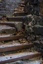 Background or texture of broken old, concrete steps on street with metal crossbars and fallen autumn, yellow leaves. Stone wall. Royalty Free Stock Photo