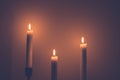 large white burning candles in dark room over wall background Royalty Free Stock Photo