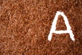 Background with texture of brown flax seeds with a white letter of vitamin A