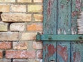 Background texture old wooden door with brown green broken paint and a yellow red brick wall Royalty Free Stock Photo