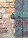 Background texture old wooden door with brown green broken paint and a yellow red brick wall Royalty Free Stock Photo