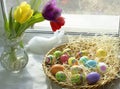 Background to the theme of Easter on the windowsill multicolored Easter eggs, tulips in a vase and a hare Royalty Free Stock Photo