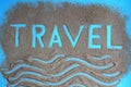 The word travel is written on the sand