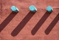 Background - Turquoise corbels and their long shadows on an orange stucco wall on southwestern style building