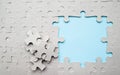 Background of the unfinished cardboard puzzle without drawing. With a big blue hole on the right and a few pieces of the puzzle. Royalty Free Stock Photo