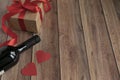 Background for Valentine`s Day. A bottle of wine, a gift from kraft paper, a heart and a satin red ribbon on a wooden background Royalty Free Stock Photo