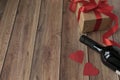 Background for Valentine`s Day. A bottle of wine, a gift from kraft paper, a heart and a satin red ribbon on a wooden background Royalty Free Stock Photo