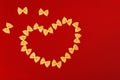 Background for Valentine`s Day. Food Valentine`s Day. Pasta farfalle bows in the shape of a heart on a red background for Royalty Free Stock Photo