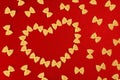 Background for Valentine`s Day. Food Valentine`s Day. Pasta farfalle bows in the shape of a heart on a red background for Royalty Free Stock Photo