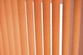 Background of vertical orange blinds curtains. Pleated roller blinds. Orange striped background