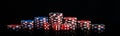 Background vertical rows of different poker chips and red dice stand on a black background long photo