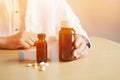 Background in warm light ,Asian man doctor holding a bottle of pills on a brown table and empty space for text. Royalty Free Stock Photo