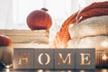 Background with warm sweaters and the inscription HOME. Pile of knitted clothes with leaves, pumpkins. Coziness. Autumn concept Royalty Free Stock Photo