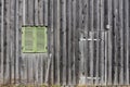 Background of a weathered wooden wall with vertical wooden slats, an old closed door and an old window with closed green shutters Royalty Free Stock Photo