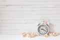 Background with white alarm clock and small pink roses on white