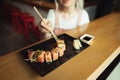 Background. Woman eats appetizing sushi roll in Japanese restaurant, takes rolls with chopsticks, cropped photo from above, Girl Royalty Free Stock Photo