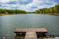 Background with wooden pier on the shore of a large lake in the forest. Wonderful spring landscape. A cozy place for rest, meditat