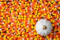 Background of yellow, orange, and white candy corn for the holidays, with a white ceramic pumpkin Royalty Free Stock Photo