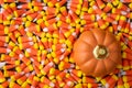 Background of yellow, orange, and white candy corn for the holidays, with an orange ceramic pumpkin Royalty Free Stock Photo