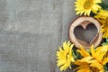 Background with yellow sunflowers and wooden heart on the canvas