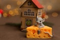 Backgrounds and textures. A toy mouse sits in cheese on a brown starry background, a small wooden house and Christmas Royalty Free Stock Photo