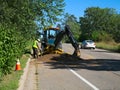 A backhoe and construction worker placing cables under street