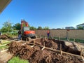 A backhoe digging a hole for a pool behind a house in Orlando, Florida