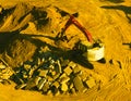 A backhoe excavator moves earth rock at a dusty construction site